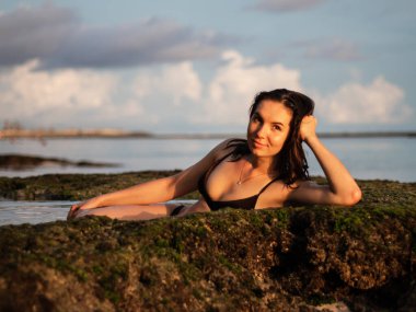 Deniz suyu banyosunda yatan genç bir kadın. Bali seyahat konsepti. Beyaz kız plajda eğleniyor. Melasti plajı, Bali, Endonezya