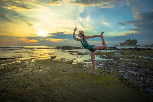 Outdoor sunset yoga. Attractive woman practicing yoga, standing in Natarajasana, Lord of the Dance Pose. Balancing, back bending asana. Bali, Indonesia — Zdjęcie stockowe