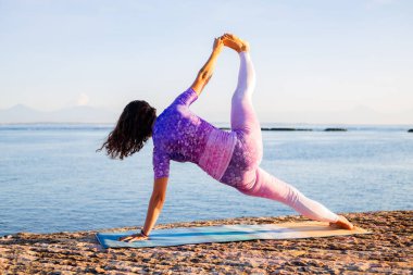 Gün doğumu yoga alıştırması. Vasisthasana II, Tek Bacaklı Yan Plank Pozu 'nu uygulayan kadın. Çekirdek ve omuzları güçlendir, dengeyi geliştir. Arkadan bak. Yoga inzivası. Kişisel bakım konsepti. Bali, Endonezya