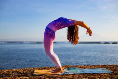 Yoga yapan genç bir kadın, Hasta Uttanasana pozunda dikiliyor, konuyu saptırıyor. Gün doğumu yoga alıştırması. Esnek omurga. Kişisel bakım konsepti, sağlıklı yaşam tarzı. Yoga inzivası. Bali, Endonezya