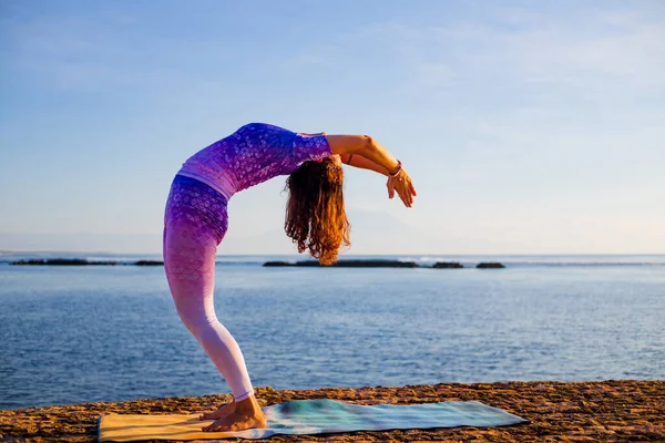 Yoga yapan genç bir kadın, Hasta Uttanasana pozunda dikiliyor, konuyu saptırıyor. Gün doğumu yoga alıştırması. Esnek omurga. Kişisel bakım konsepti, sağlıklı yaşam tarzı. Yoga inzivası. Bali, Endonezya