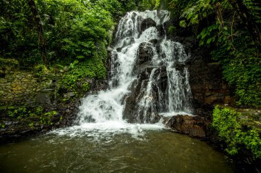 Şelale manzarası. Tropikal yağmur ormanlarında saklı güzel bir şelale. Orman nehri. Macera ve Asya 'ya seyahat. Ambengan, Bali 'de Jembong şelalesi. Yavaş deklanşör hızı, hareket fotoğrafçılığı.