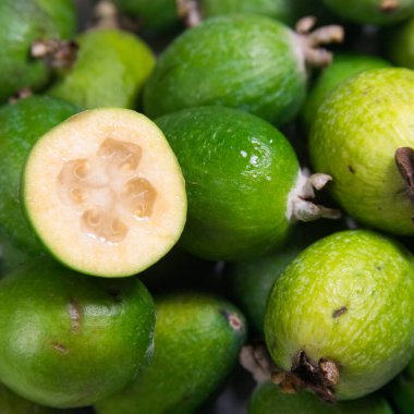 Fayjoa 'nın geçmişi. Meyve soyut arka plan. Beyaz arka planda Feijoa. Tam bir feijoa ve dilimlenmiş meyve.