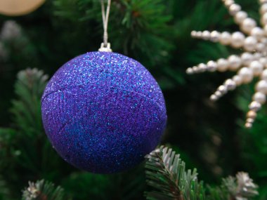 Noel ağacının yeşil dalında asılı koyu mavi parlak top. Işıklar ve çelenkler. Noel ve mutlu yıllar konsepti, dizaynınız için metin alanı. Duvar Kağıdı