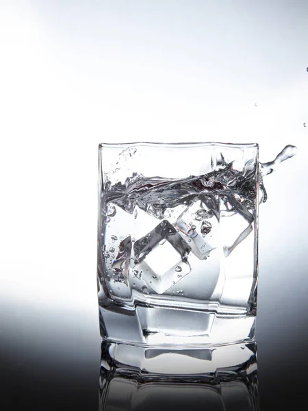 Een Glas Water Met Plons Van Vallende Ijsblokjes Witte Achtergrond — Stockfoto