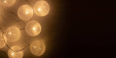 Parlayan beyaz toplar. Siyah arka planda parıldayan bir çelengi olan bir tatil için ev dekorasyonu