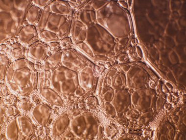 Sabun köpüklerinin Macro 'su hücre ve hücre zarının bilimsel görüntüsüne benziyor. turuncu arkaplan