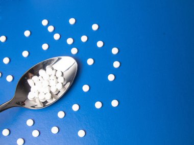 Çeşitli ilaç hapları, haplar ve kapsüller. Geçmiş haplar. Çeşitli ilaç tabletleri ve kaşığın üzerine haplar. Arka planda farklı renkler. Sağlık hizmetleri