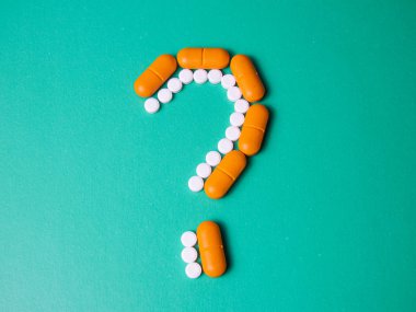 Pembe arka planda haplardan ve kapsüllerden yapılmış bir tabela. Mavi arka planda haplar. Soru işareti. - İntihar. Uygunsuz tedavi yüzünden ölüm. Tehlikeli uyuşturucular. Uzayı kopyala Yukarıdan görüntüle. 