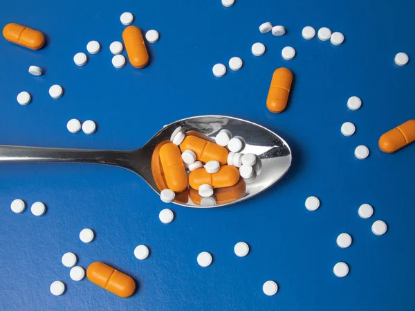 medicine pills, tablets and capsules. Blue background. Heap of assorted various medicine tablets and pills on spoon different colors on background. Health care