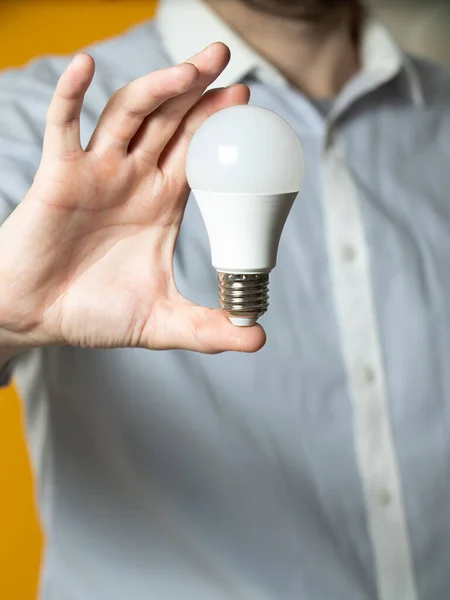 The hand of a man holding a light bulb for innovation and creative concept. Light bulb in hand on a yellow background. Empty space for your text
