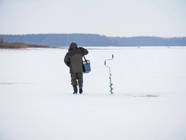 Winter ice fishing, lake, frosty day. fisherman collects gear in the snow