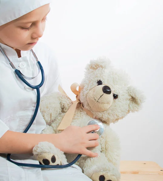 Evde pelüş oyuncakla doktorculuk oynayan sevimli çocuk. Çocuk doktorculuk oynuyor ve içeride pelüş oyuncakları iyileştiriyor. beyaz üzerine izole