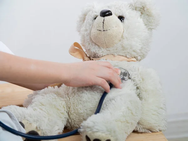 Evde pelüş oyuncakla doktorculuk oynayan sevimli çocuk. Çocuk doktorculuk oynuyor ve içeride pelüş oyuncakları iyileştiriyor. beyaz üzerine izole