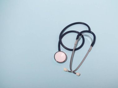 Tıbbi steteskop ya da fonendoskop açık mavi arka planda izole edilmiş. Stetoskop yakın plan. Düz yat. Metnin burada.
