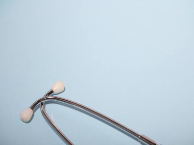 Tıbbi steteskop ya da fonendoskop açık mavi arka planda izole edilmiş. Stetoskop yakın plan. Düz yat. Metnin burada.