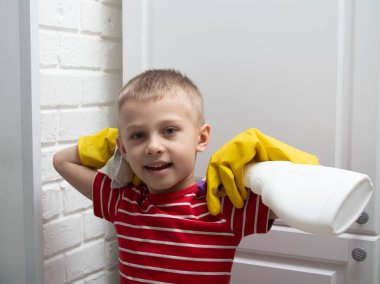 Sarı lastik eldivenli bir çocuk temizlik yapıyor. Çocuk mobilyaları tozdan ve pislikten temizliyor. Beşinci adım.