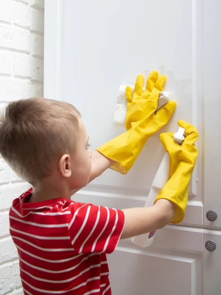 a child in yellow rubber gloves is cleaning. the child wipes the furniture from dust and dirt. Step 2