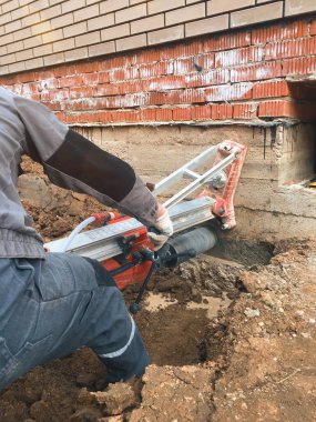 Betonda elmas sondaj makinesi deliği. Bir matkap, elmas bir taç kullanarak beton bir binanın temelinde bir delik açar.