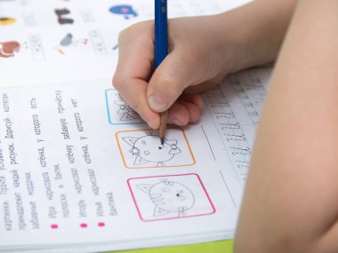 Moskova / Rusya - 04.01.2020: Bir çocuk ev ödevini yapıyor. Karantinada uzaktan öğrenme. Ders kitapları, defterler masanın üstünde. Kalemle çocuk eli.