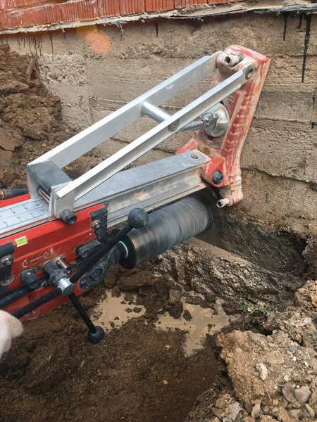 Betonda elmas sondaj makinesi deliği. Bir matkap, elmas bir taç kullanarak beton bir binanın temelinde bir delik açar.
