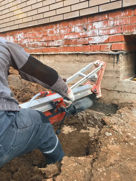 Betonda elmas sondaj makinesi deliği. Bir matkap, elmas bir taç kullanarak beton bir binanın temelinde bir delik açar.