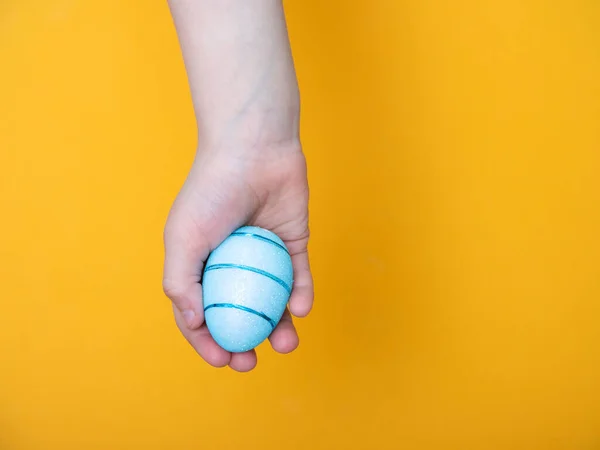 Moscow/Russia - 04.01.2020 : children\'s hands hold Easter eggs on a yellow background. space for your text