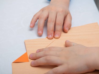 Talimatlar adım adım. Karantina sırasında evde eğitim gören bir çocuk kağıttan origami yapar. Çocukların yaratıcılığı. Eller yukarı.