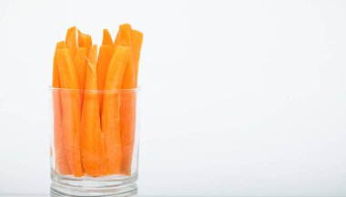 Beyaz arka planda bir bardakta kesilmiş taze havuçlar.