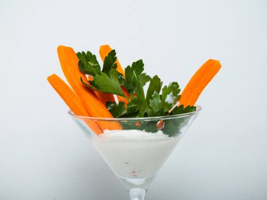 Ekşi kremalı taze havuç. Beyaz arka planda bir bardakta dilimlenmiş.