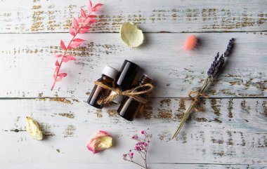 Beyaz ahşap masa manzaralı gül, ot ve lavanta şişeleri