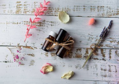 Beyaz ahşap masa manzaralı gül, ot ve lavanta şişeleri