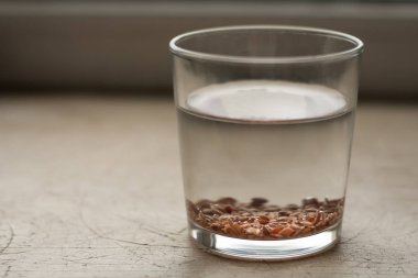 Flax seeds are soaked in a glass with water for germination clipart