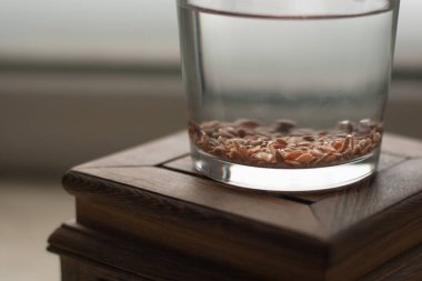 Flax seeds are soaked in a glass with water for germination clipart