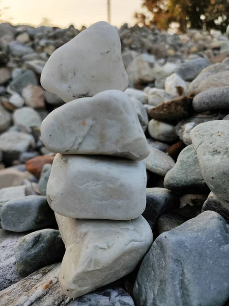 Stack of triangular stones.Group of white and colorful Stones.Pebble tower on the stones seaside.Stones pyramid on pebble beach symbolizing stability,zen,Rock,harmony,balance.Shallow depth of field.