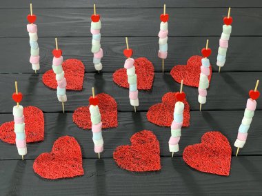 Siyah arka plandaki şişte renkli marşmelovlar.