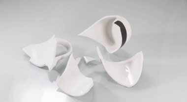 Kırık beyaz bardak, beyaz üzerine. Kırık çatal bıçak parçaları. Boş bir kase parçalara ayrılır..