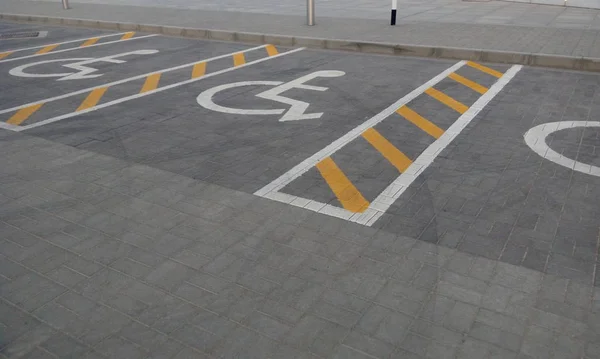 Tekerlekli sandalyedeki kişi için ayrılmış engelli park yeri olan asfalt yol.