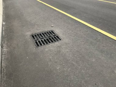 Bir Ağır Görev Izgara Kapağı, İngiliz Standartları 'na uygun olarak karayolu ve altyapı alanlarının drenajı ve şeritler için sarı çizgili asfalt yollar için bir üstgeçit köprüsünde sabitlendi.