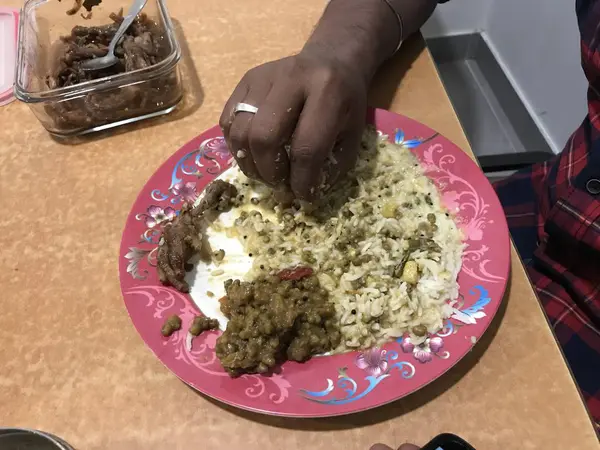 Ein Indianer isst Reis mit ganzem grünen Gramm auf einem rosafarbenen Teller und isst mit bloßen Händen, was hygienisch oder unhygienisch ist — Stockfoto