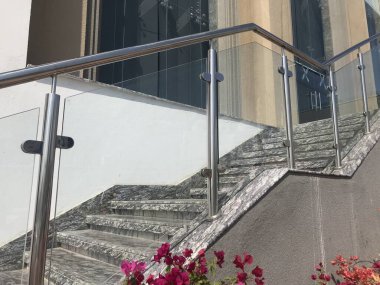 stainless steel chrome plated finished hand rails with glass panels for an ramp or staircase steps for an building interiors for better protection to avoid people falling clipart