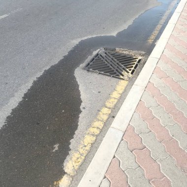 Toprağın dengesiz yerleşimine yol açan sıkıştırmadaki kötü işçilikten dolayı rögar kapağından su çekiliyor.