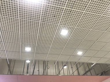 Macro Grid False ceiling around gypsum finished under progress which expose pink gypsum board furring channels supports and threaded rod clipart