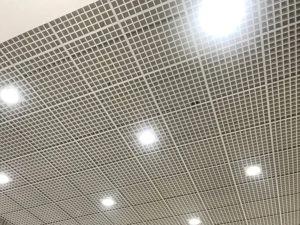 Finished Gypsum and Macro grid false ceiling with attractive down lights at equal spacing for and large open area of an shopping mall interiors