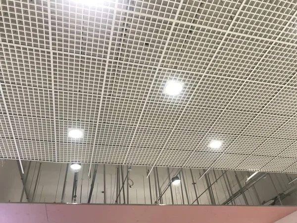 Macro Grid False ceiling around gypsum finished under progress which expose pink gypsum board furring channels supports and threaded rod