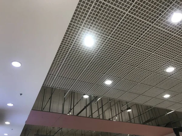 Macro Grid False ceiling around gypsum finished under progress which expose pink gypsum board furring channels supports and threaded rod