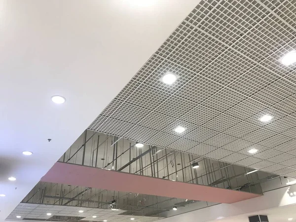 Macro Grid False ceiling around gypsum finished under progress which expose pink gypsum board furring channels supports and threaded rod