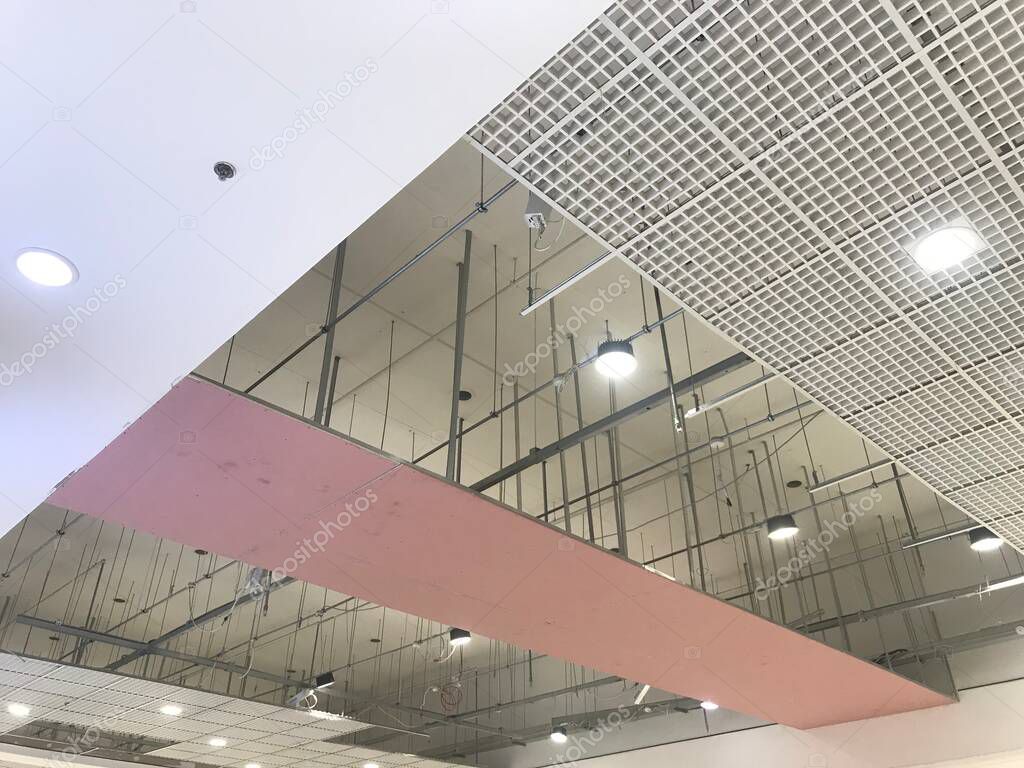 Macro Grid False ceiling around gypsum finished under progress which expose pink gypsum board furring channels supports and threaded rod