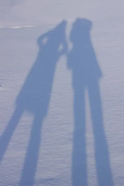 牵着手在雪地里制造影子 — 图库照片