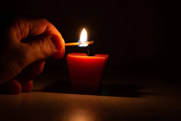 Рука з сірником запалює свічку в темряві. Пам'ятна подія . — стокове фото